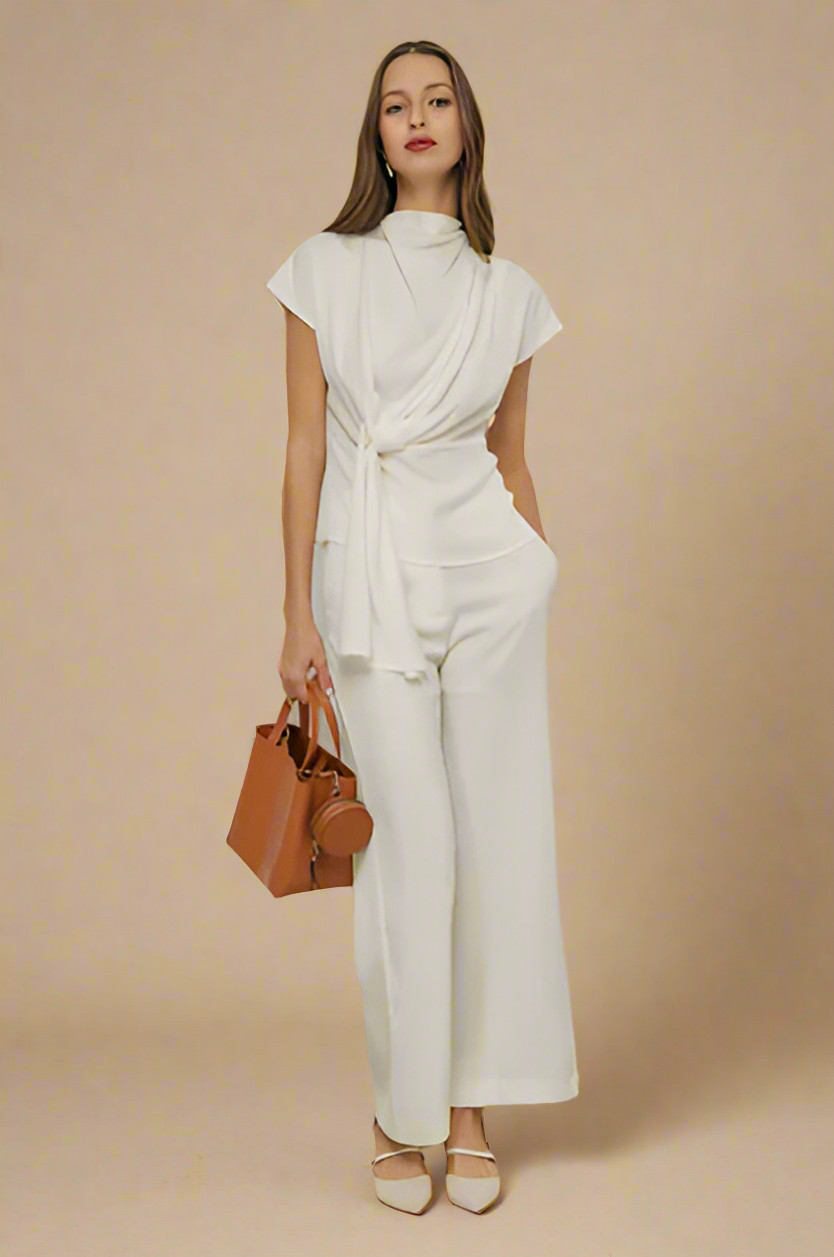 Woman wearing a white outfit with a brown handbag on a beige background