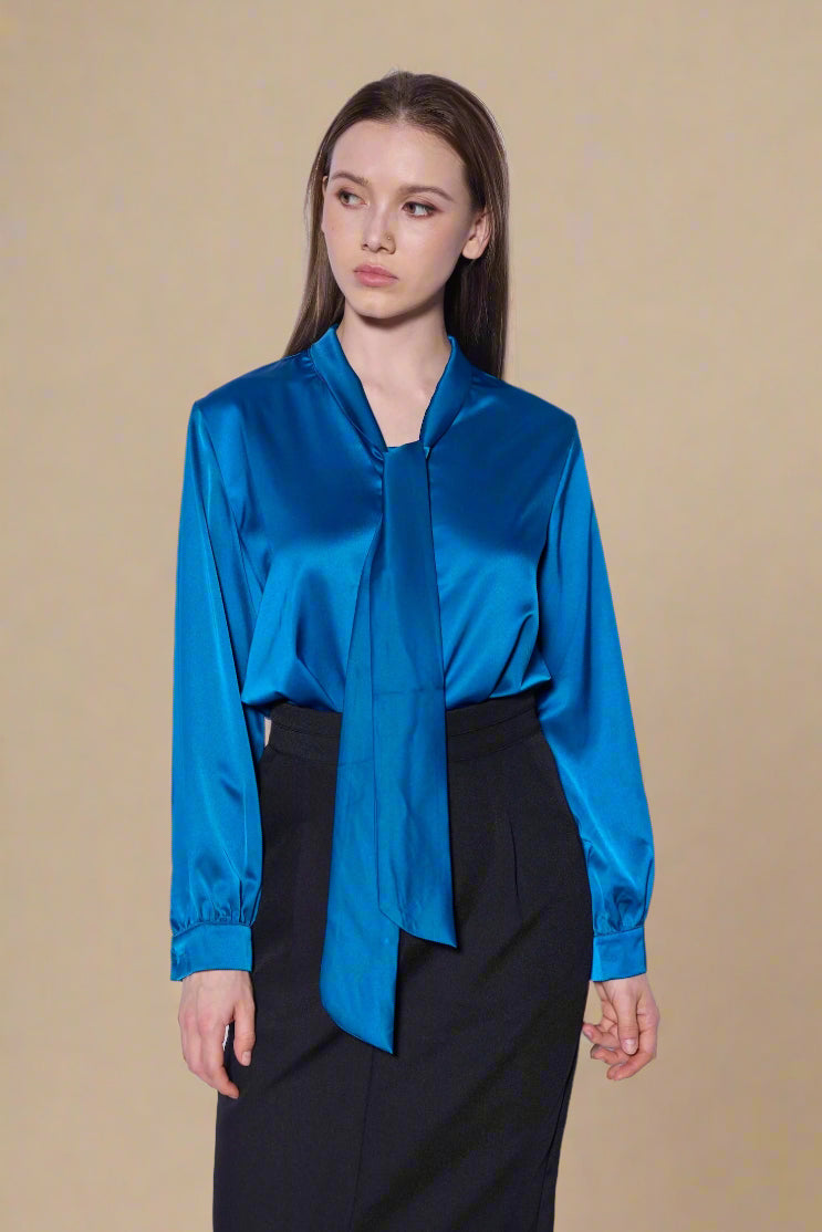 Woman wearing a blue satin blouse and black skirt against a white background
