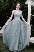 Woman in a light blue dress standing outdoors with greenery in the background