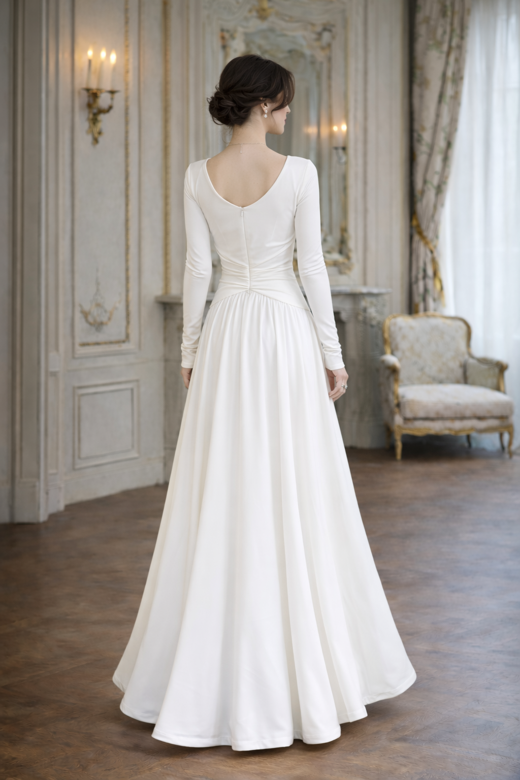 Woman in a white wedding dress standing in an elegant room with a mirror and chair.